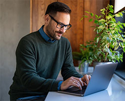 Adulto joven sentado viendo su laptop | Modalidad Executive de UDLA